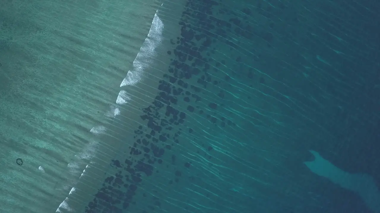 High vertical aerial looks down onto waves breaking