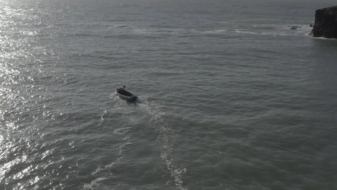 Open outboard crab fishing boat turns left into spectral sun beam