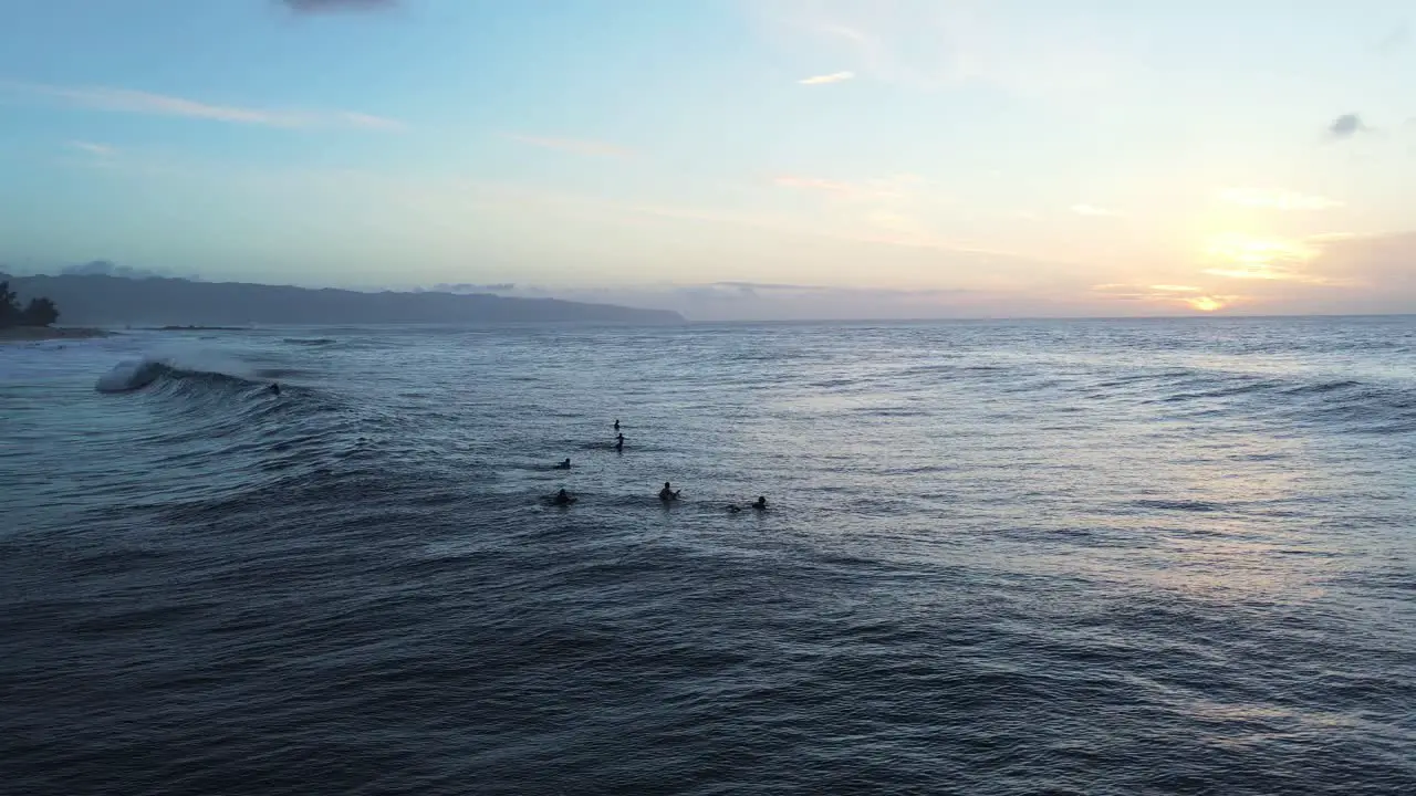 Surfers waiting for big sea wave at sunset North coast Oahu island Hawaii