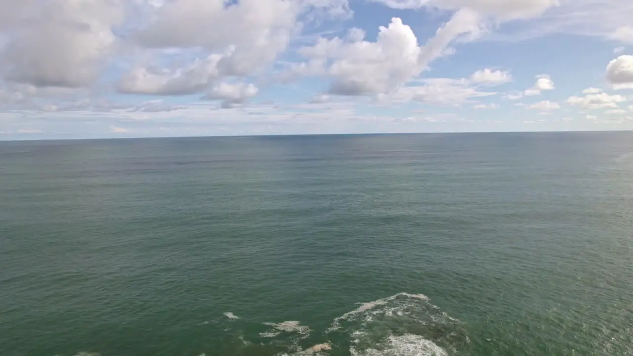 Aerial dolly in rising over rocky shore and turquoise sea on a cloudy day in in Dominicalito Beach Costa Rica