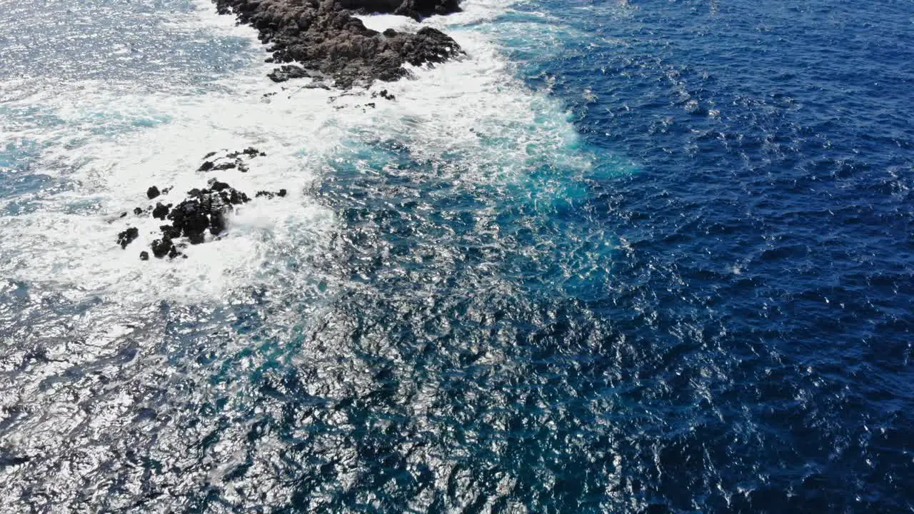 Top Down View Of Foamy Sea Waves Splashing On Rocks In The Middle Of The Ocean aerial drone shot