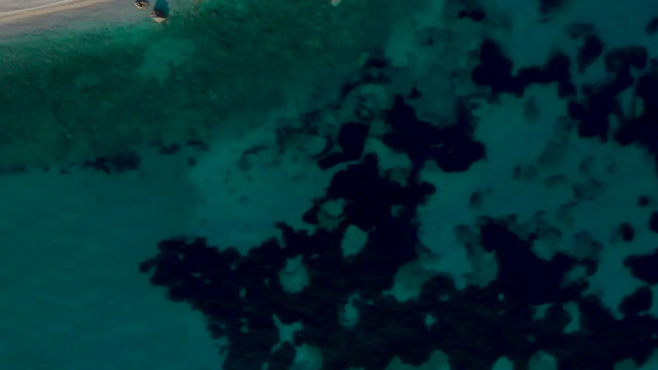 Seabed pattern under turquoise water near paradise beach with pebbles and rocks top down view