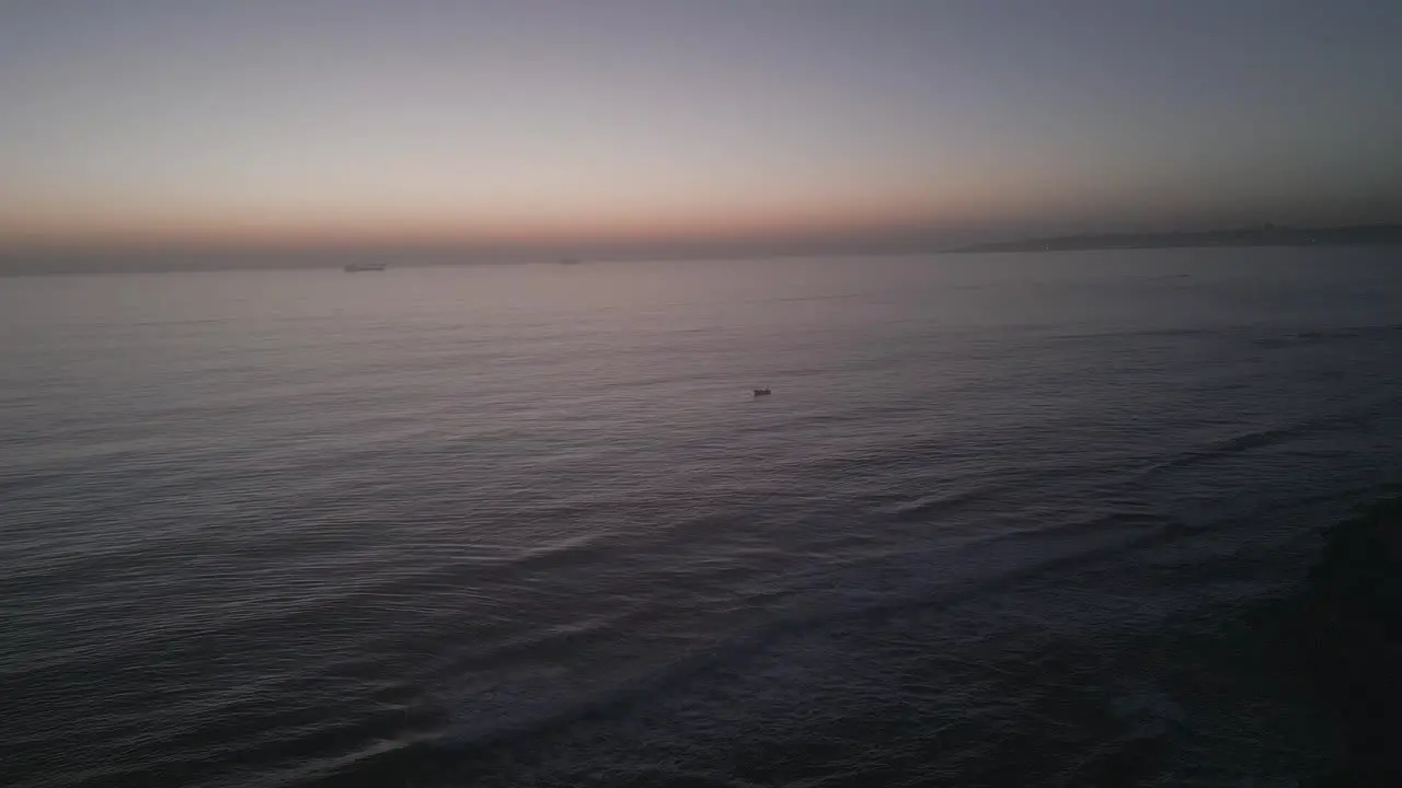 Sailboat glides across the water during orange sunset