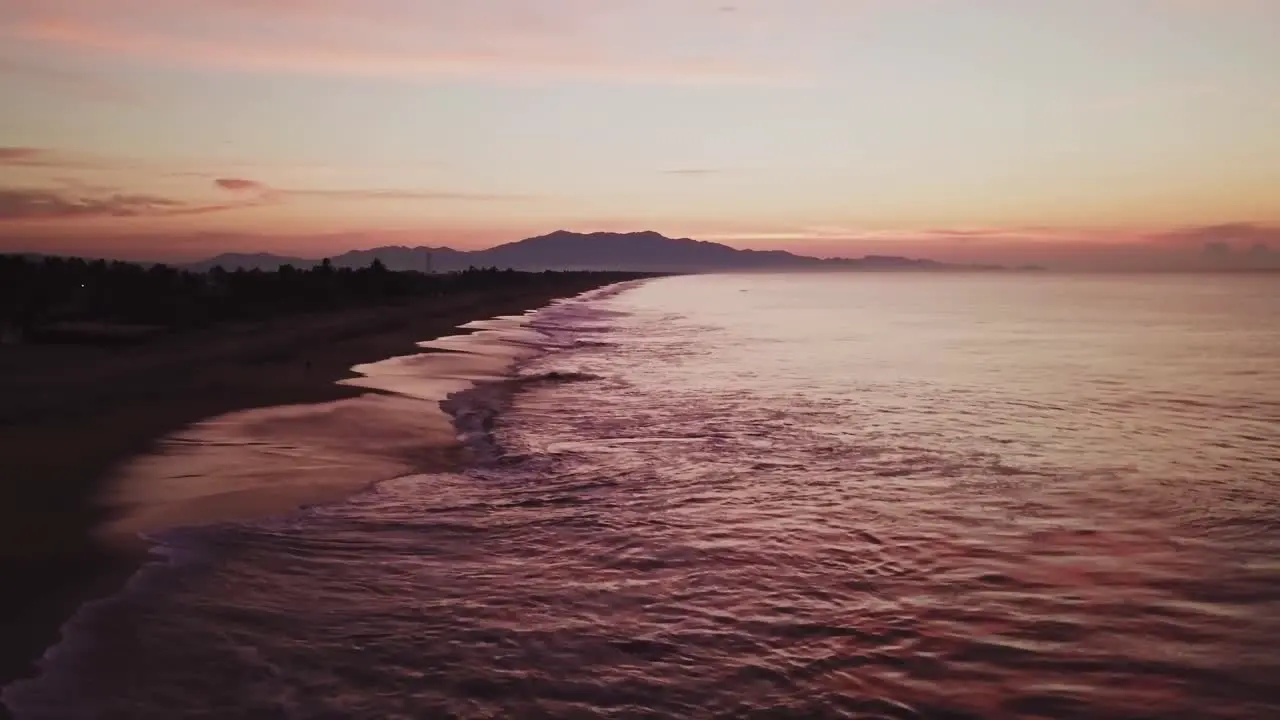 Aerial low angle static shot above sea waves at beach seaside in Mexico at dusk