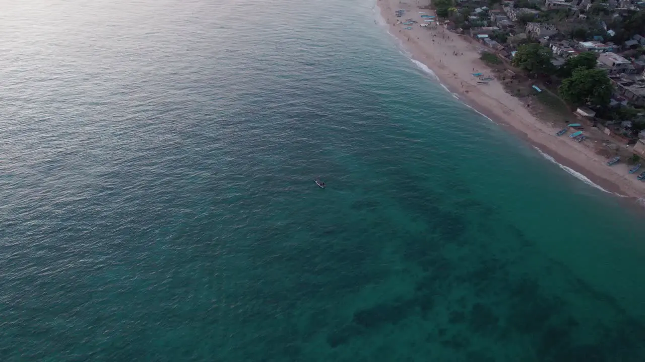 fishing close by rural beach village above corals aerial rotating view