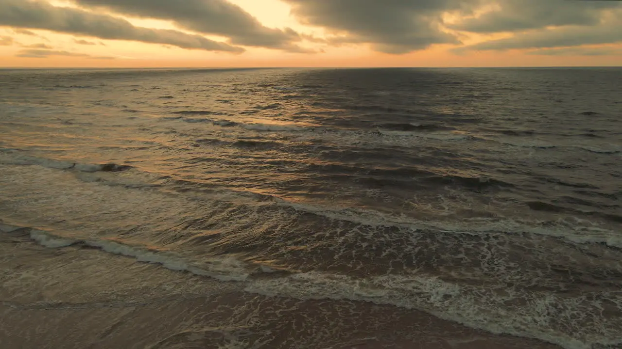 Sundown aerial view of waves breaking on shore dramatic seascape drone shot