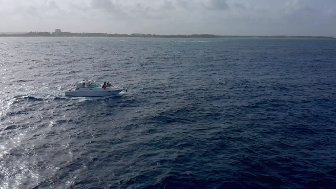 Shot with drone in the open sea to a white boat with people on board in cap cana