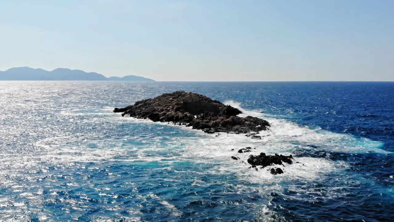 Blue Foamy Waves Crashing On Rocks At Jerusalem Beach In Greece aerial drone shot