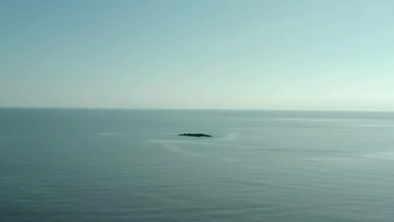 Birds eye view of single rock island in middle of nowhere at ocean