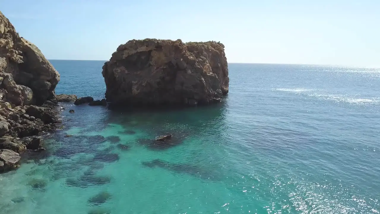 Tilt up shot of a big rock close the coast in the mediterranean sea