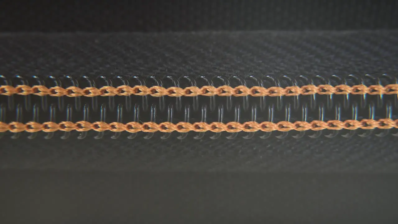 A macro close-up shot of a hard case zipper being opened orange yellow strings metal zip black box photography gear professional studio lighting static 4K video