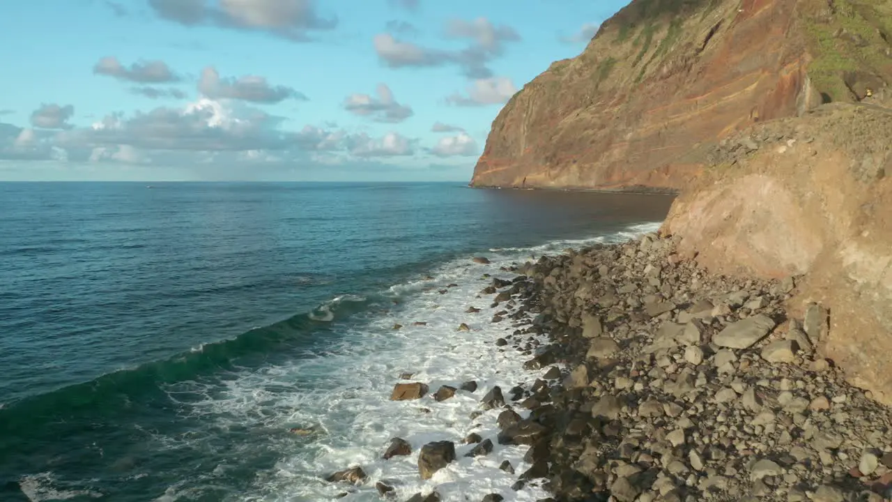 Waves breaking on beach filled with large volcanic boulders in Madeira