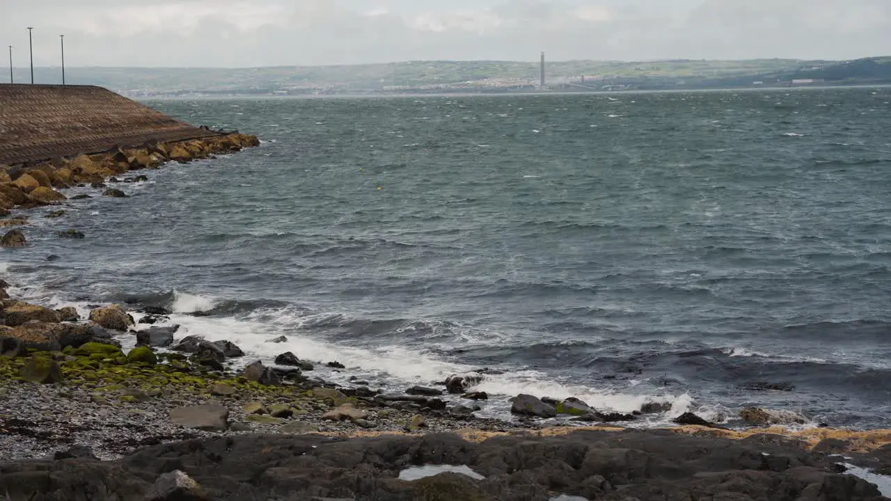 Waves crashing against rocky beach with mossy stones on windy day Bangor Northern Ireland