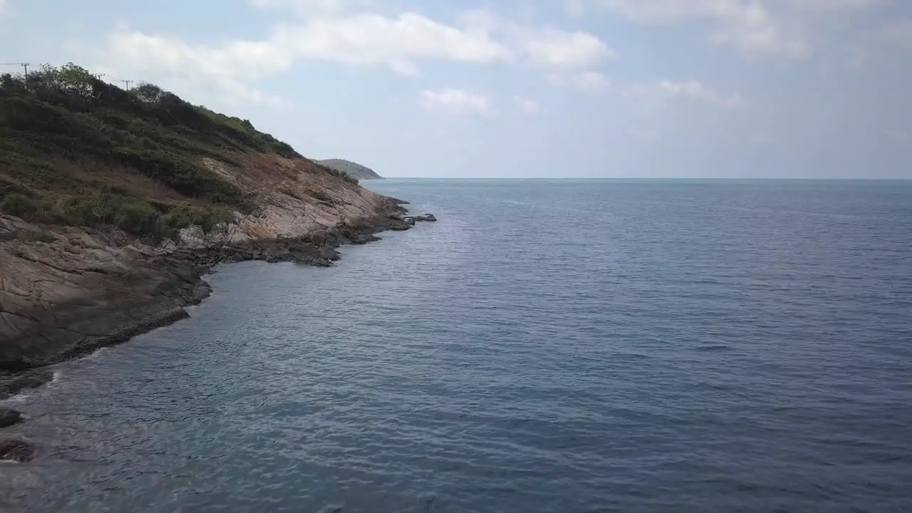 Aerial landscape view of a rocky beach a small hill on the left side  with waves coming from the ocean