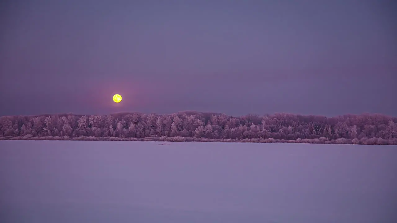 Timelapse shot of snow covered winter landscape with moon rising during evening time