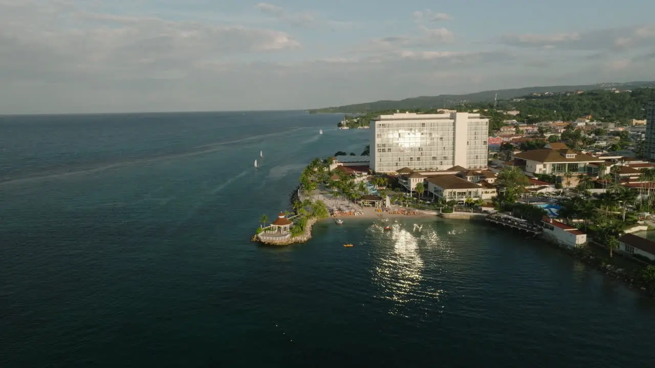 Golden hour dolly across luxury resort with gleaming glass water reflections off the coast of Jamaica