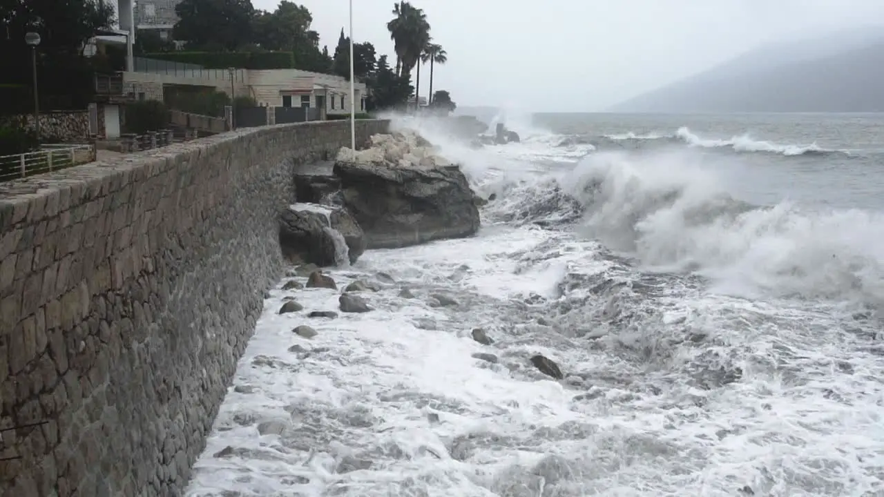 strong waves crash against the breakwater on the coast of the city