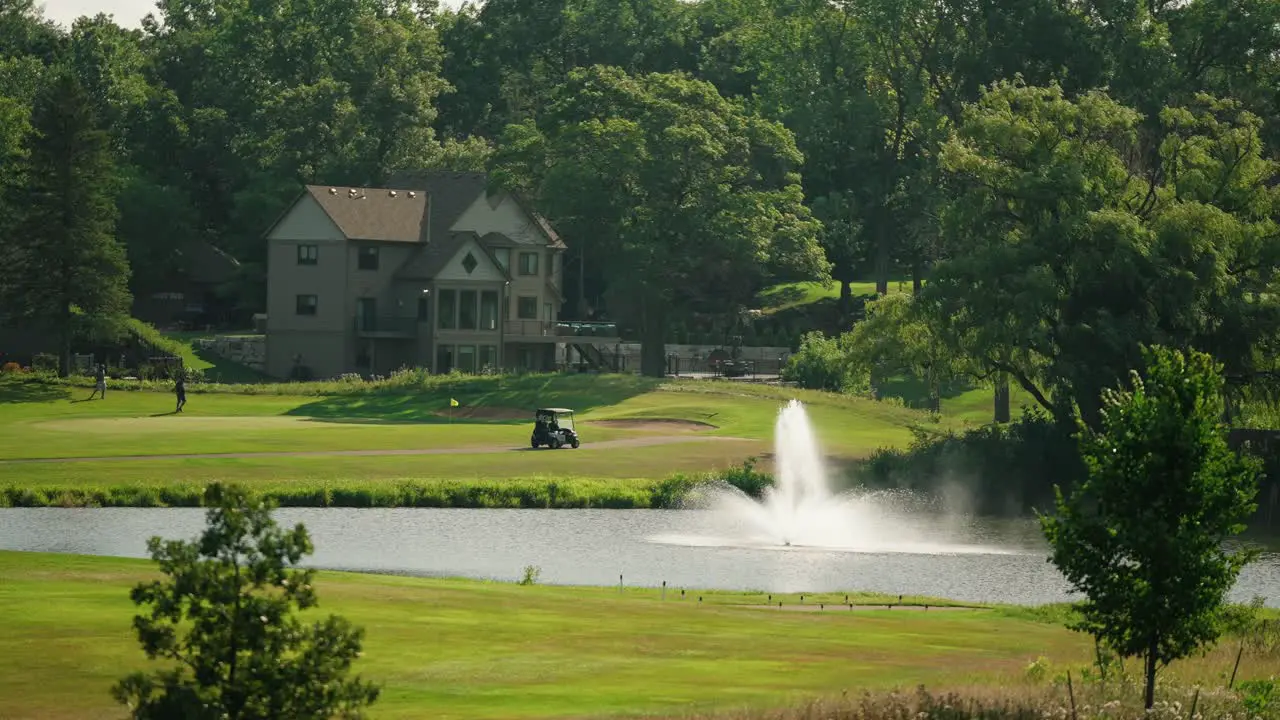 Golf cart parked next to a green with a foreground fountain inside a pond