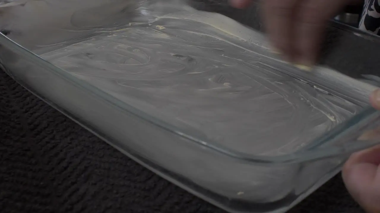 Adult Female Greasing Inside Of Pyrex Dish With Butter