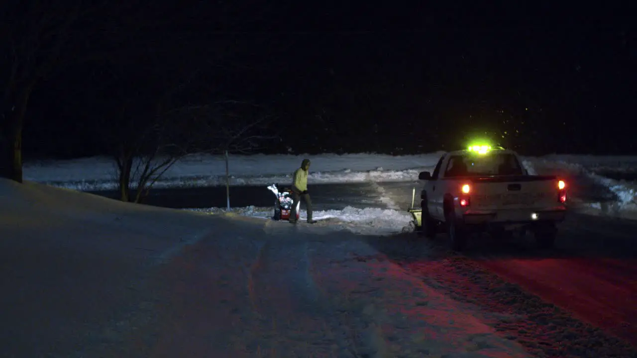 Plow man and plow truck plowing snow on road at night