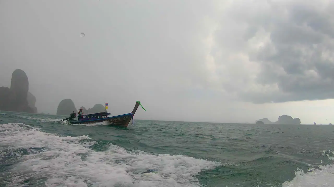 SLOW MOTION | Boat caught in rainstorm in Thailand with dark grey sky and islands in the background