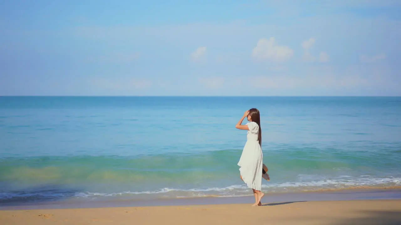 Beautiful girl walks on seashore dressed in white