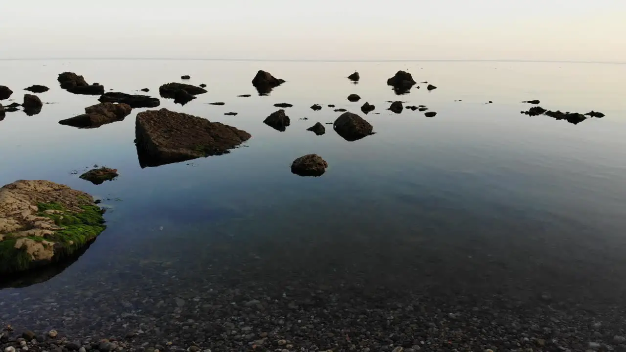 Aerial Low Flying Over Calm Serene Tranquil Waters With Rocks Poking Through