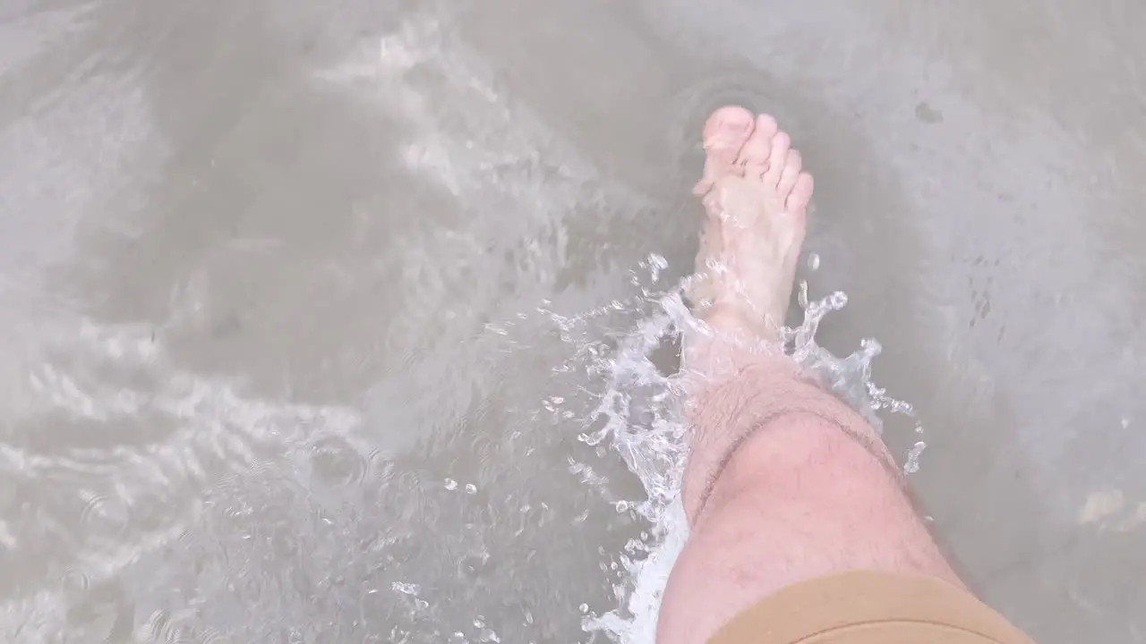 Man Barefoot in Shorts Walks in the Clear Shallow Salt Lake Water in Utah