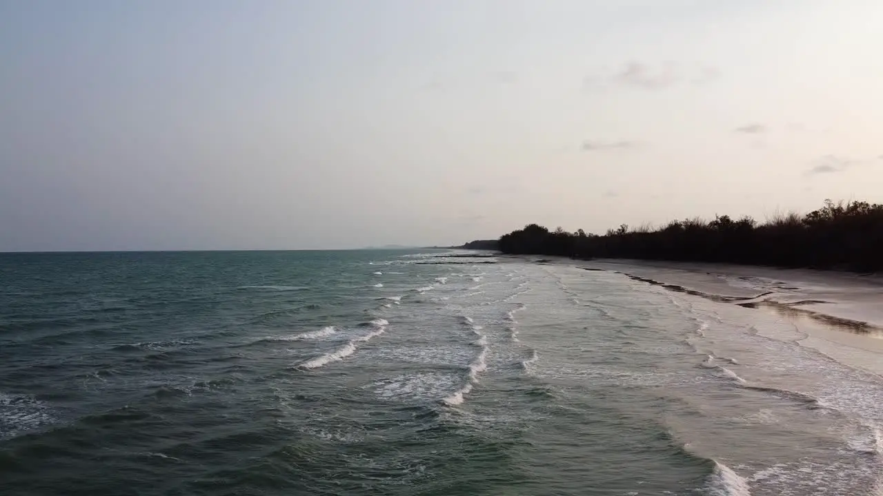 Aerial time lapse side view of Long Ocean waves reach the shore in Southern Thailand