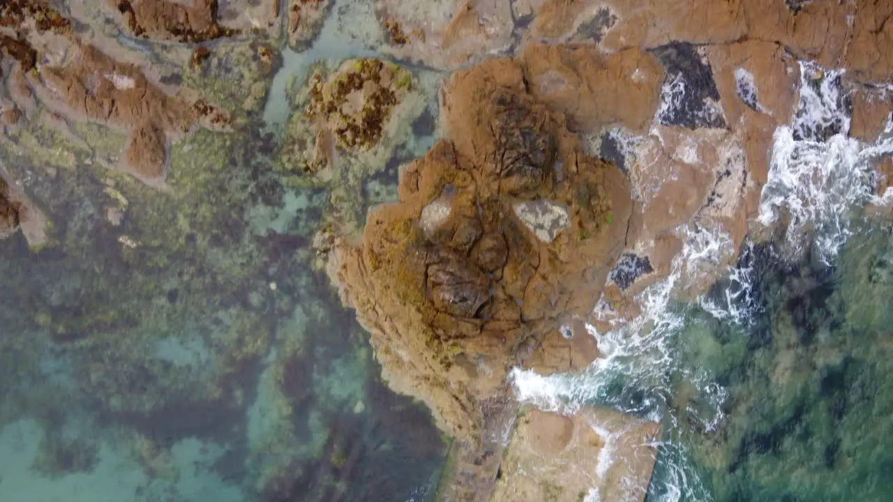 Aerial top-down forward over waves breaking on rocky coast of Saint-Malo in Brittany France