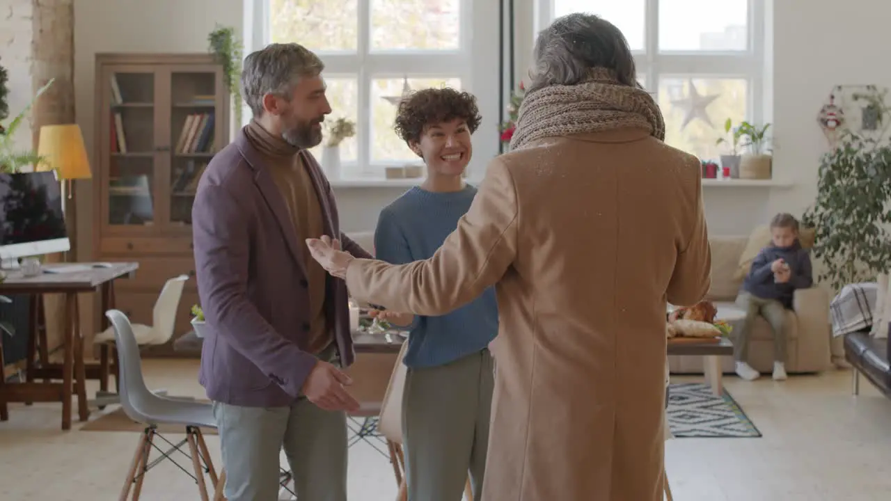 Couple Welcomes Two Friends In The Living Room With Christmas Decorations