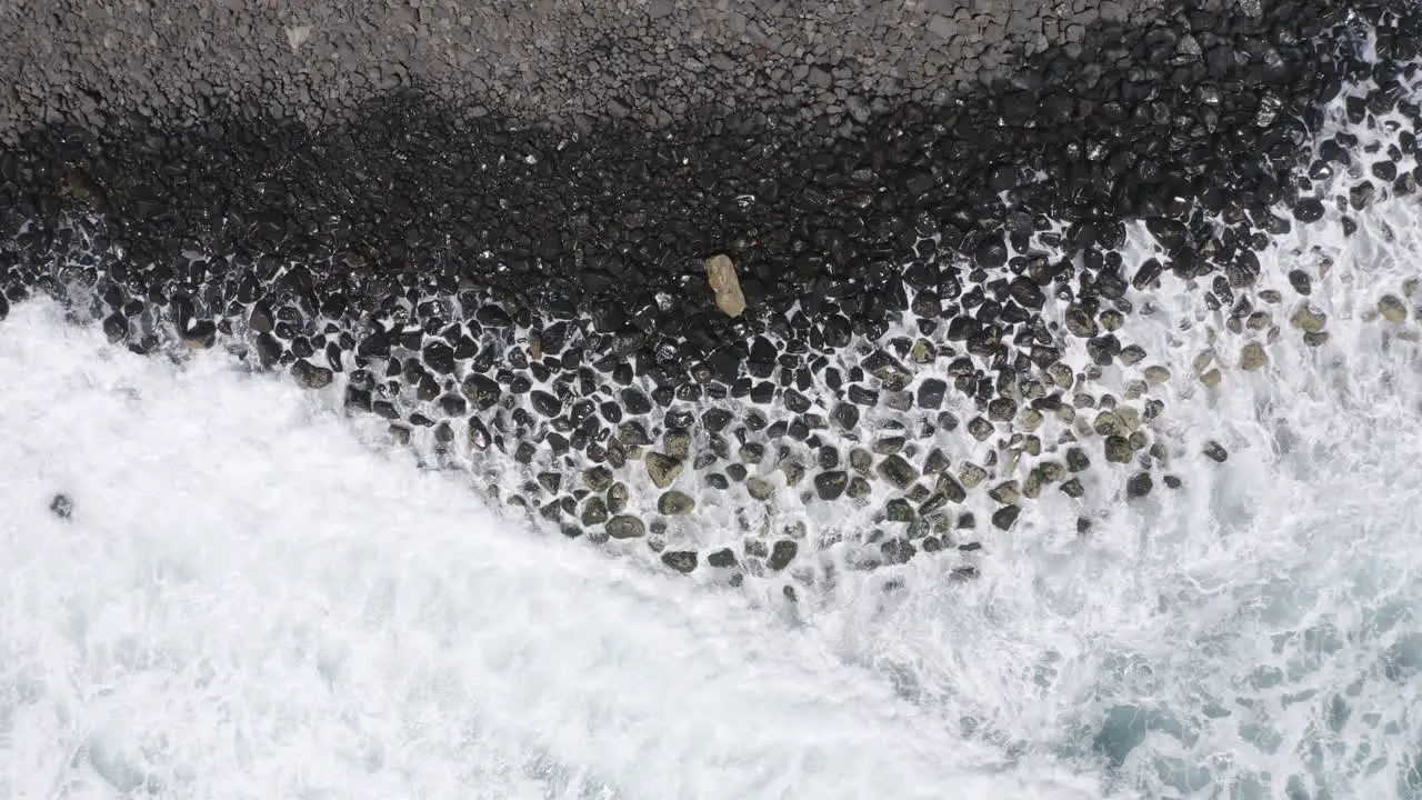 4k Drone top view shot of ocean waves crashes on a coastline with dark rocks in Australia