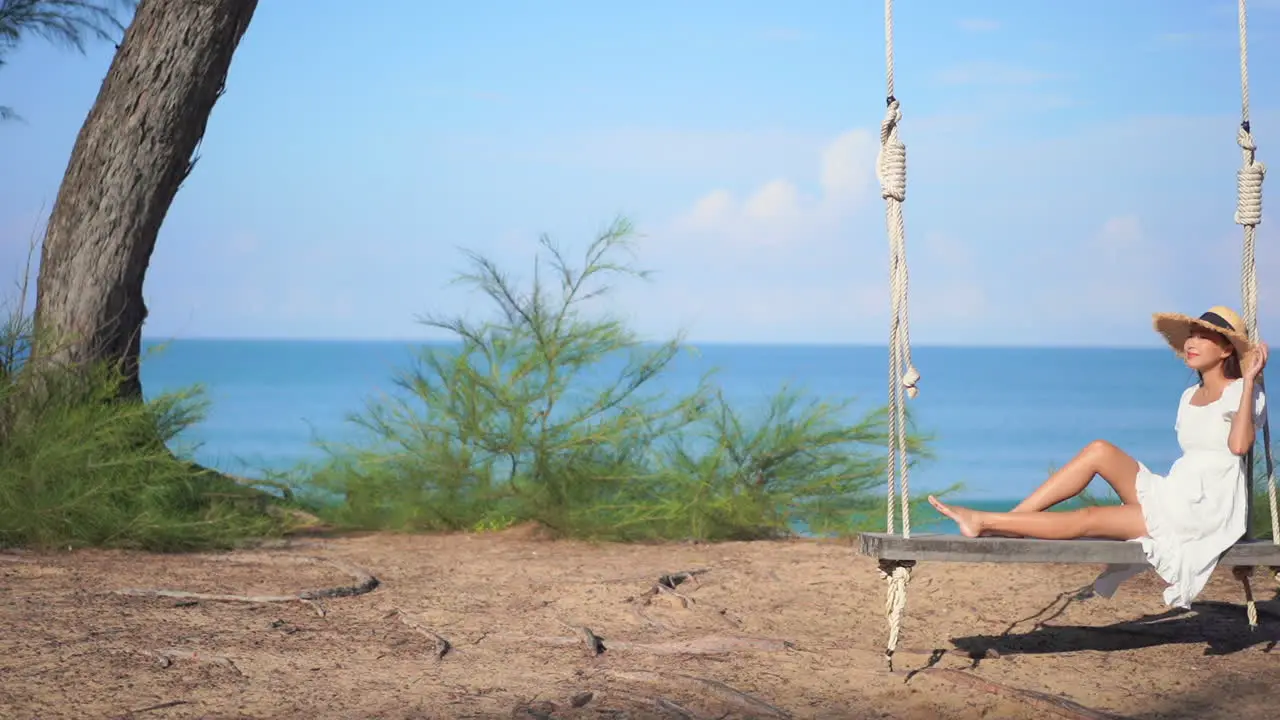 Relaxed Woman Sitting on Swing with Ocean Background