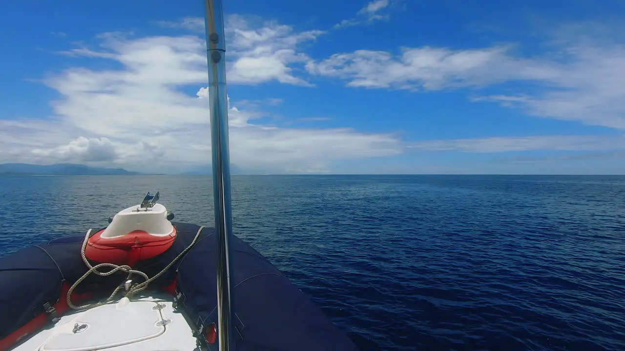 POV shot out front of small boat cruising towards distant tropical island