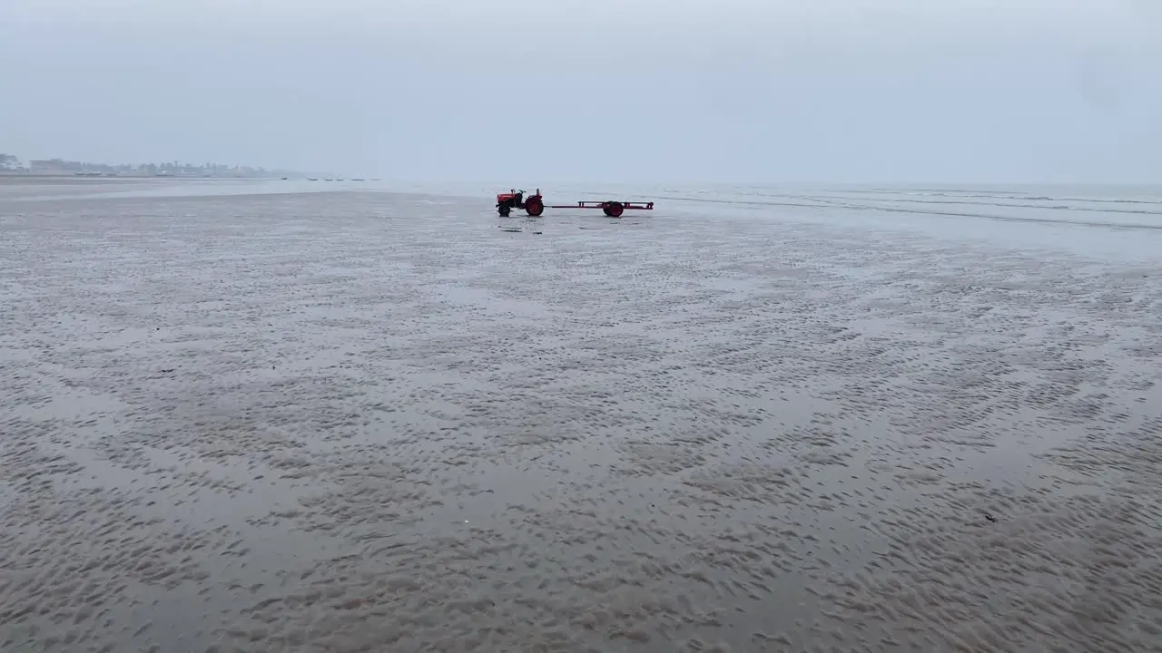 Cinematic gimble forward shot of a surreal empty sea beach with a tractor standing alone with sand loaded in a wintery evening