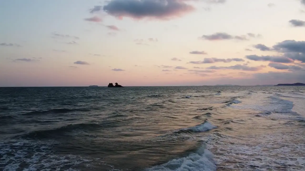 Aerial flying forward above ocean waves with Tropical islands on the background in Rayong Southern Thailand