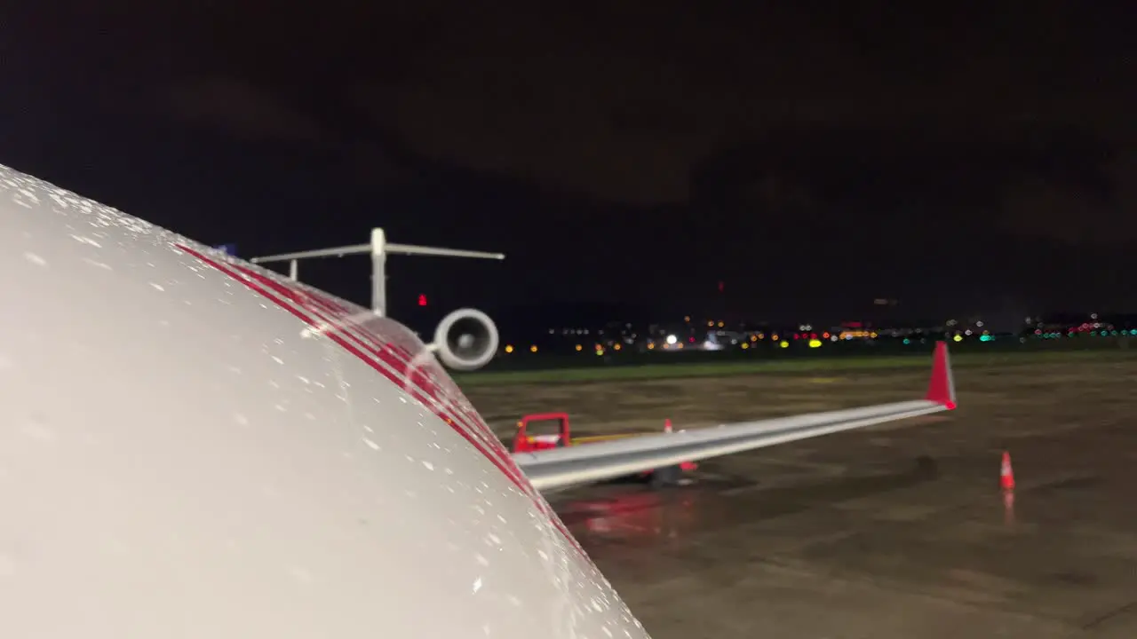 Night view of the upper part of the fuselage of a jet in a rainy and cold night with other traffics in the airport