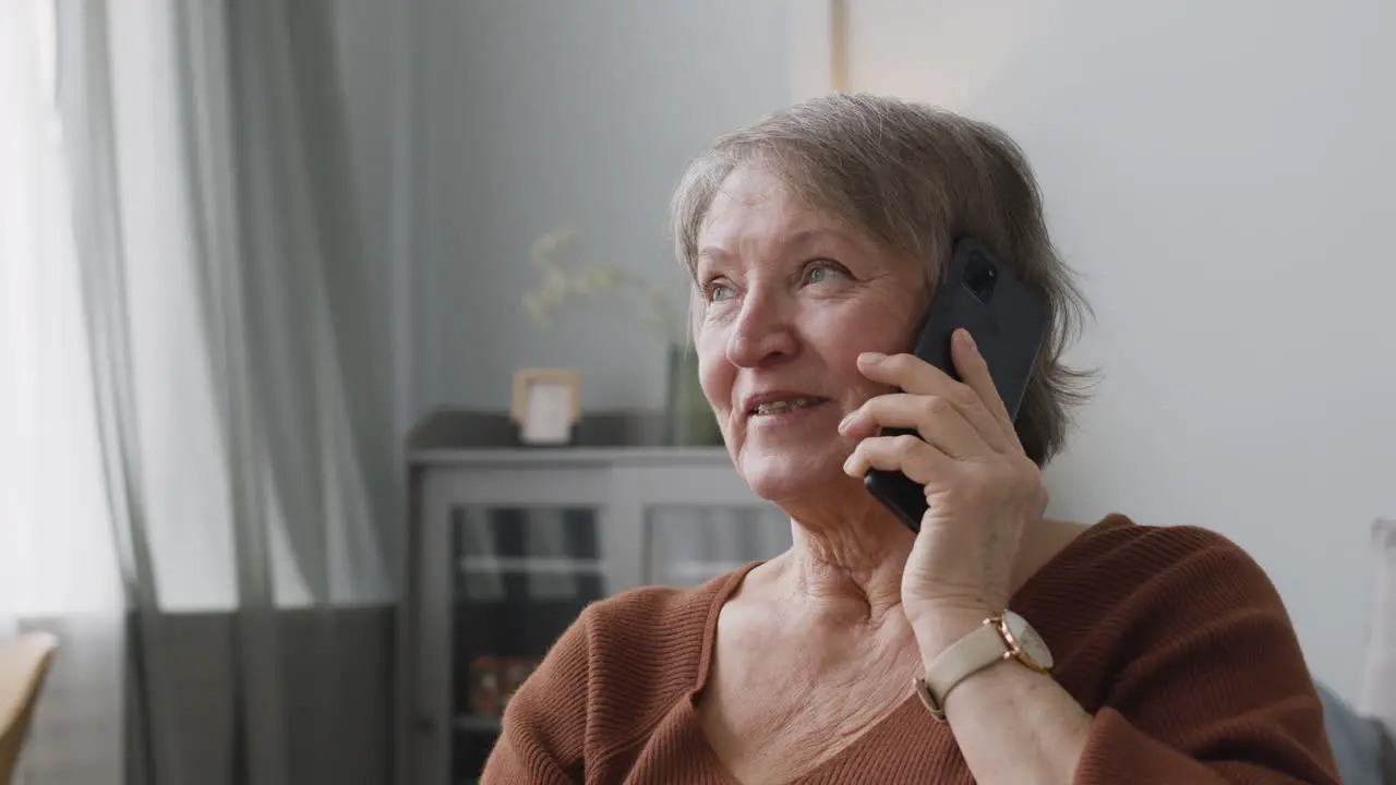 Anciana Llamando Por Teléfono Inteligente Sentada En Casa 1