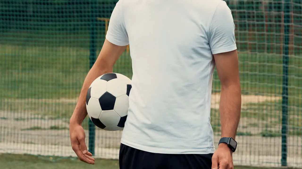 Primer Plano De Un Jugador De Fútbol Irreconocible De Pie Y Sosteniendo Un Balón De Fútbol En Un Campo De Fútbol Callejero