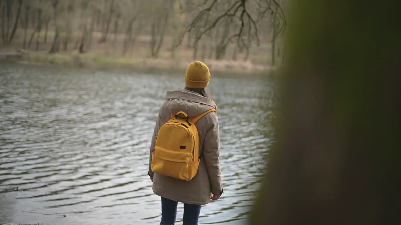 Ein Junges Mädchen In Einem Wald Das Eine Gelbe Wollmütze Und Einen Gelben Rucksack Trägt Und Den See Betrachtet