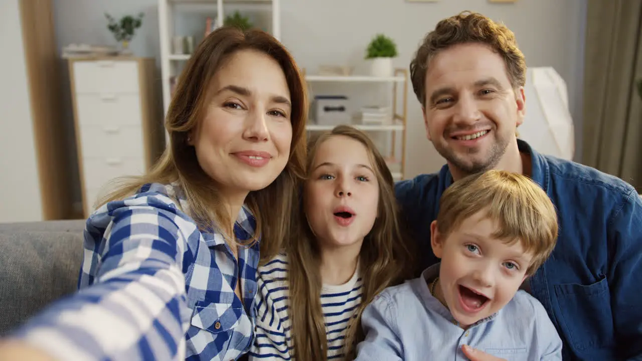 Pov Of The Nice Young Family Sitting In The Cozy Living Room And Having Videochat With Somebody