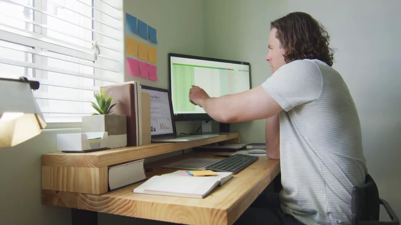 Focused caucasian man working remotely using laptop and talking on smartphone