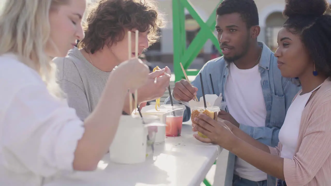 Group Of Cheerful Friends Eating Street Food In The City While Chatting And Having Fun Together