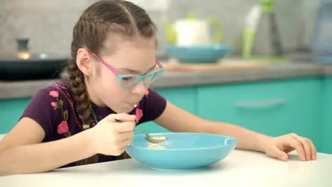 Girl eating cornflakes at kitchen Portrait of child eating healthy food