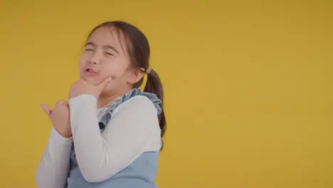 Studio Portrait Of Young Girl Thinking Against Yellow Background 