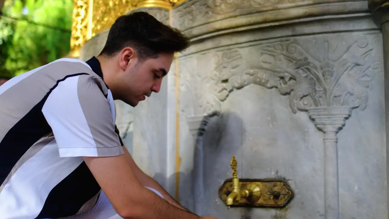 Medium Shot of Young Man Washing Hands in a Hagia Sophia Fountain