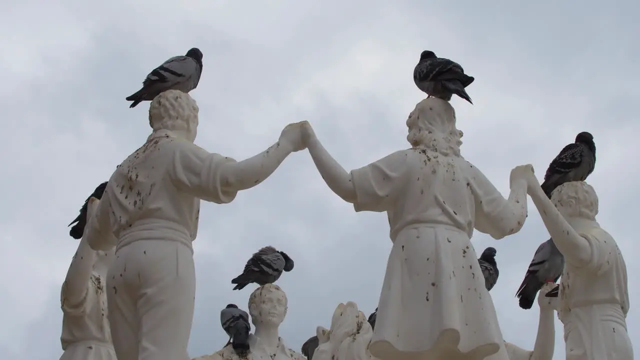 Pigeons perched on some dancing statues