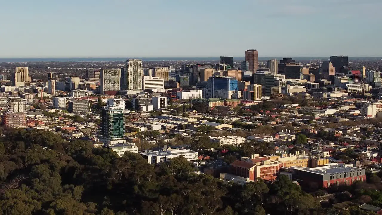 Drone shot of the Adelaide CBD moving left to right and getting closer to the city with the Adelaide Parklands in the foreground