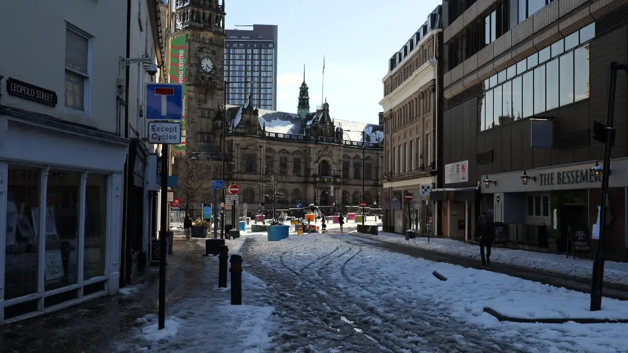 People walking in snowy sunny city centre streets Sheffield