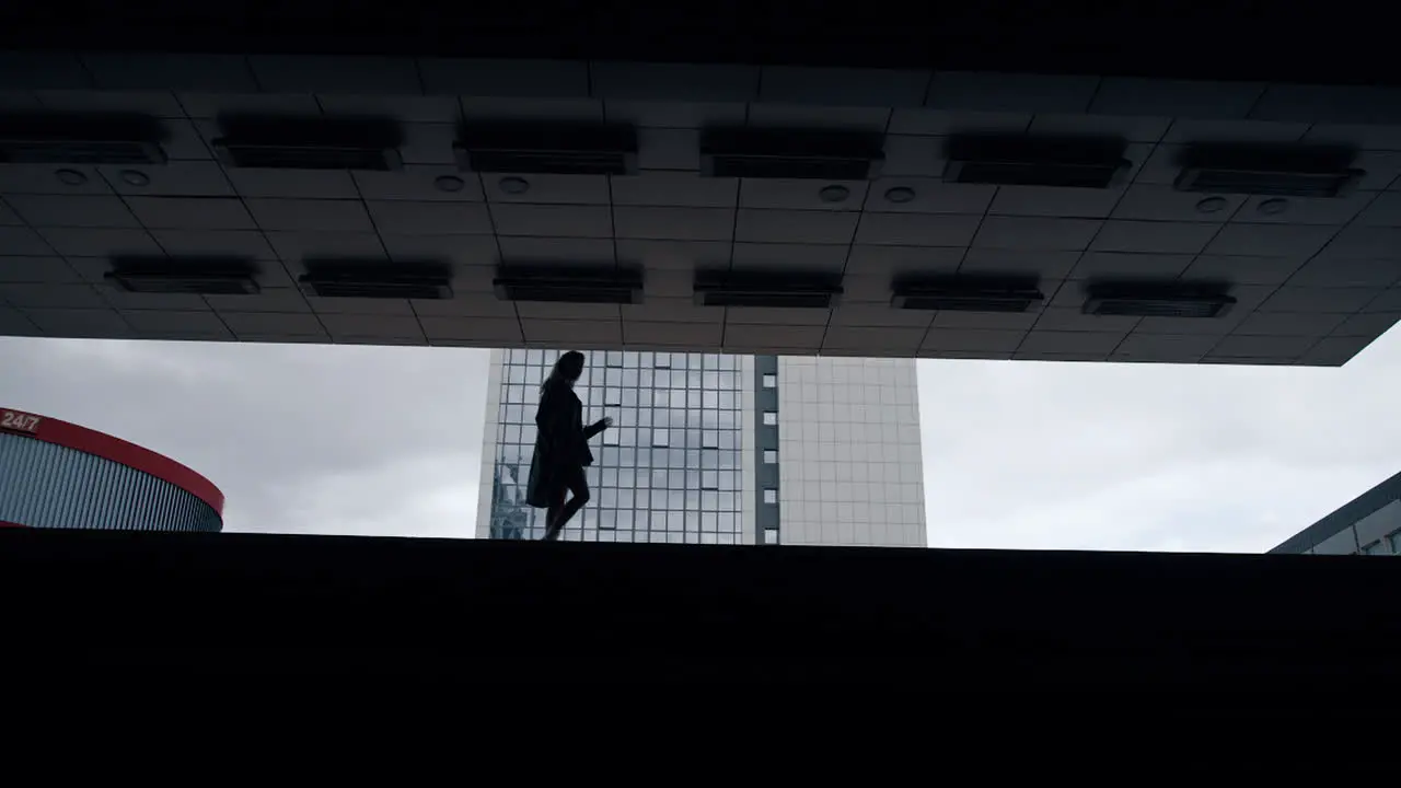 Silhouette female person walking in dark building at city downtown